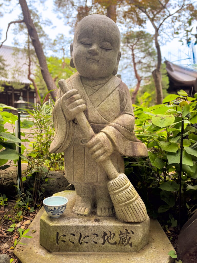 ほうき地蔵と緑に囲まれた境内 / Smiling Jizo statue with broom surrounded by greenery