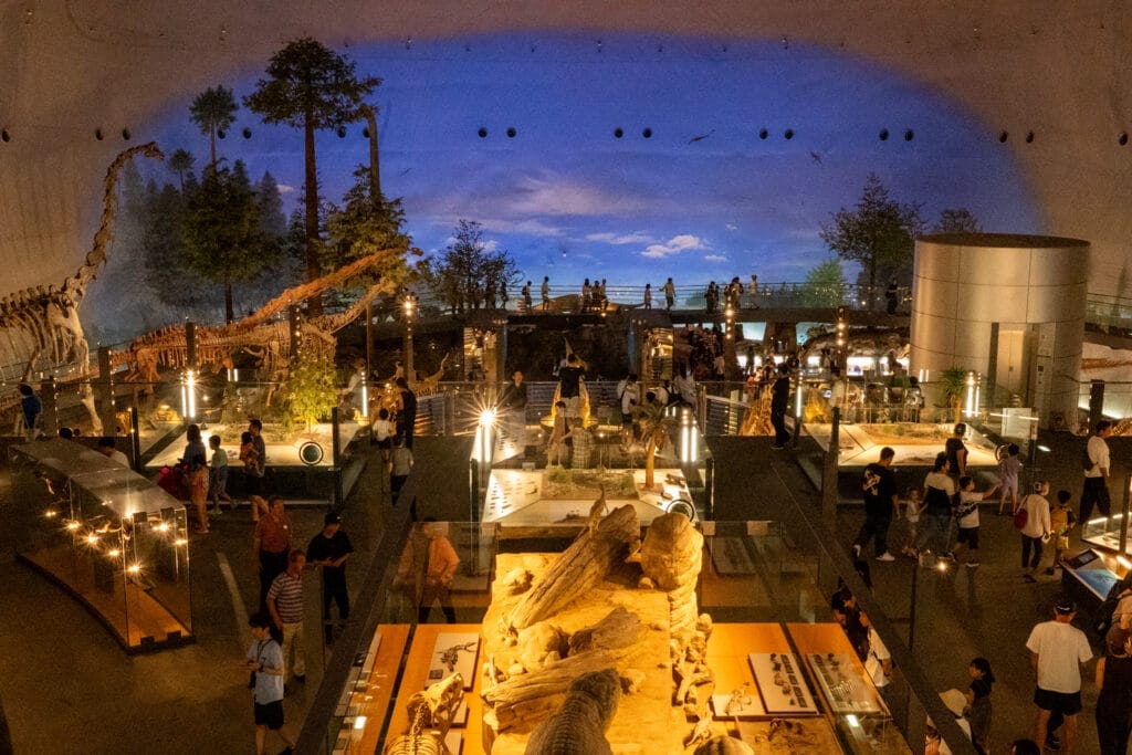 福井県立恐竜博物館の展示ホール全景。恐竜の骨格標本が並び、多くの来館者が行き交う臨場感あふれる館内風景