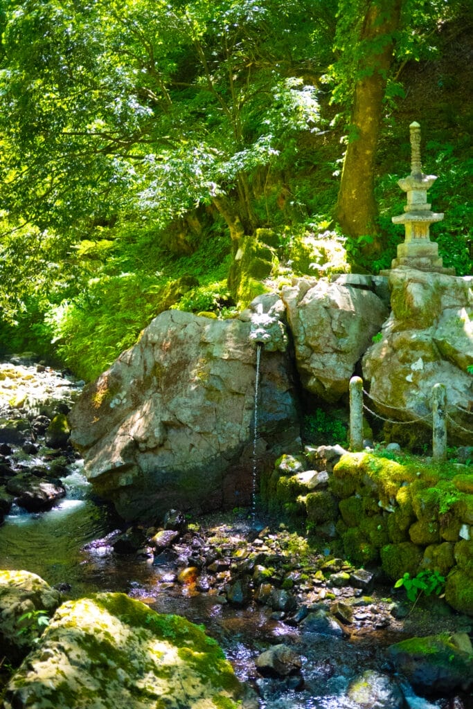 永平寺の境内にある石塔と、岩の間から流れ落ちる清らかな水。 